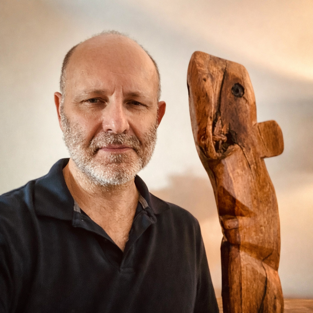 Carved oak self-portrait with exaggerated facial asymmetries, elongated proportions, natural wood grain visible throughout