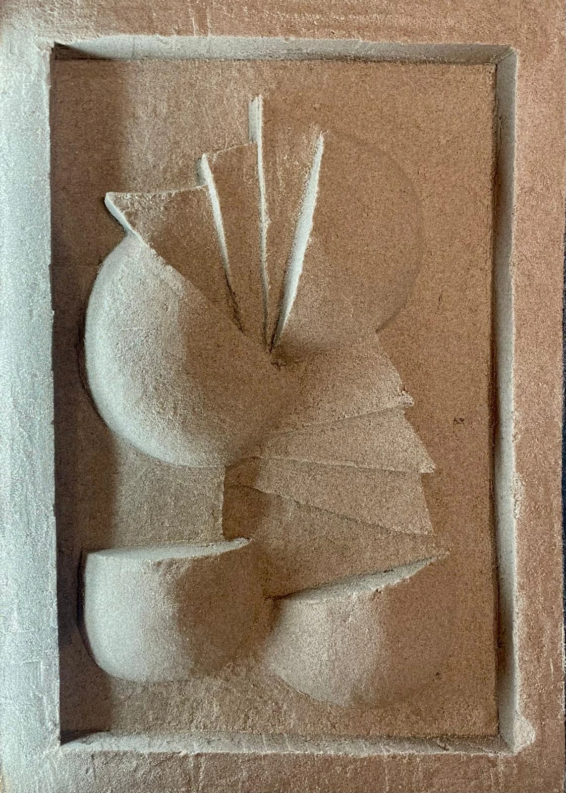 Bas-relief en sable dans un caisson en bois : quatre demi-sphères et six triangles s'enroulant depuis un pivot central